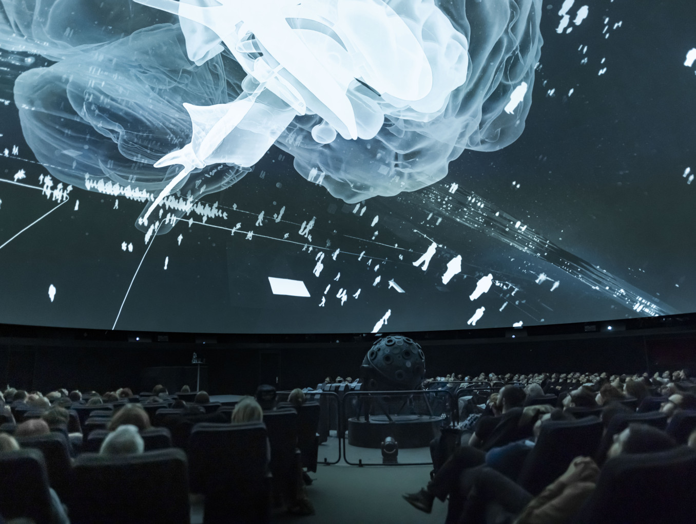 Room shot of people in a planetarium watching a projection on the ceiling