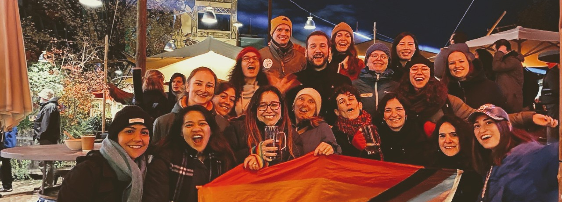 Soapbox Science Berlin and LGBTQ+ STEM Berlin teams pose with pride flag at Holzmarkt 25.