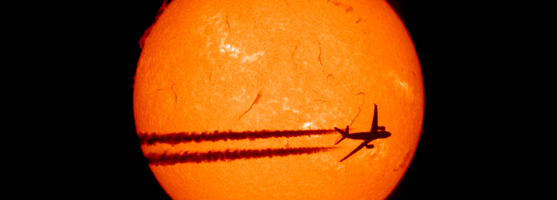 A plane crossing the sun, only its shadow visible