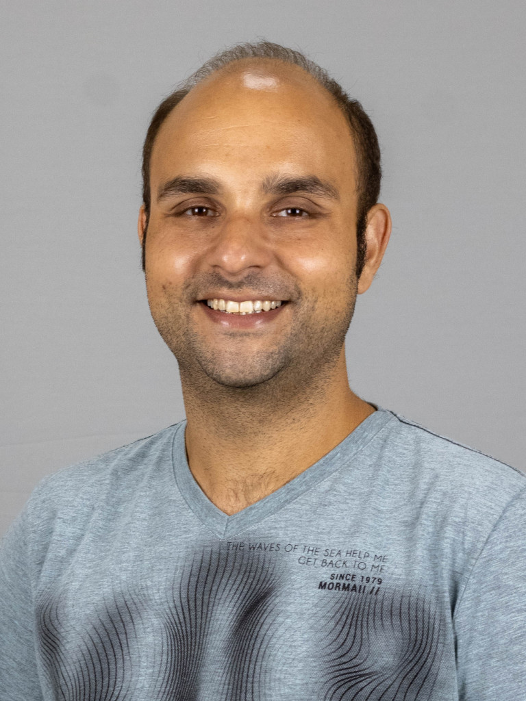 Dr. Rafael Valadares poses for the camera on a grey background