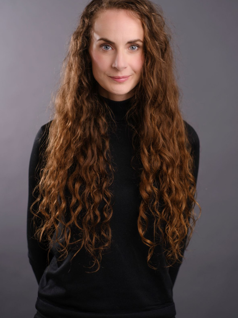 portrait of Summer Banks, a white lady with long, curly, red-brown hair. she is wearing a turtleneck that once belonged to her grandmother but you really can't tell by looking at it. but that's the great thing about alt text. it opens up new possibilites