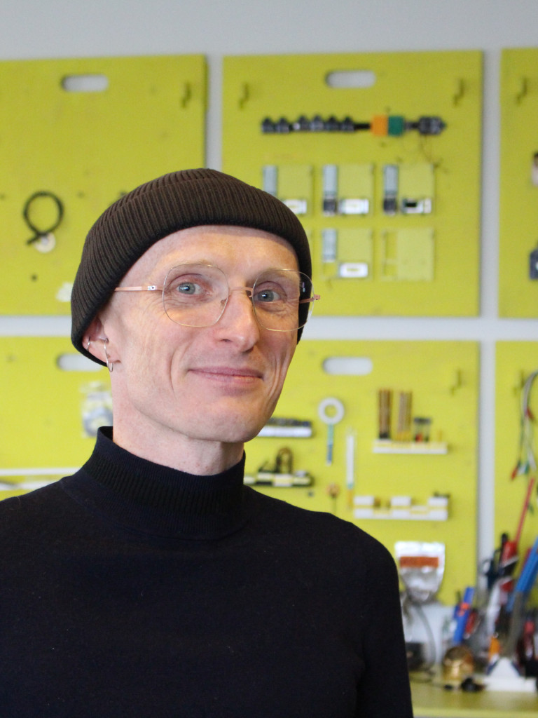 A portrait of a person with a black beanie hat and glasses. 
