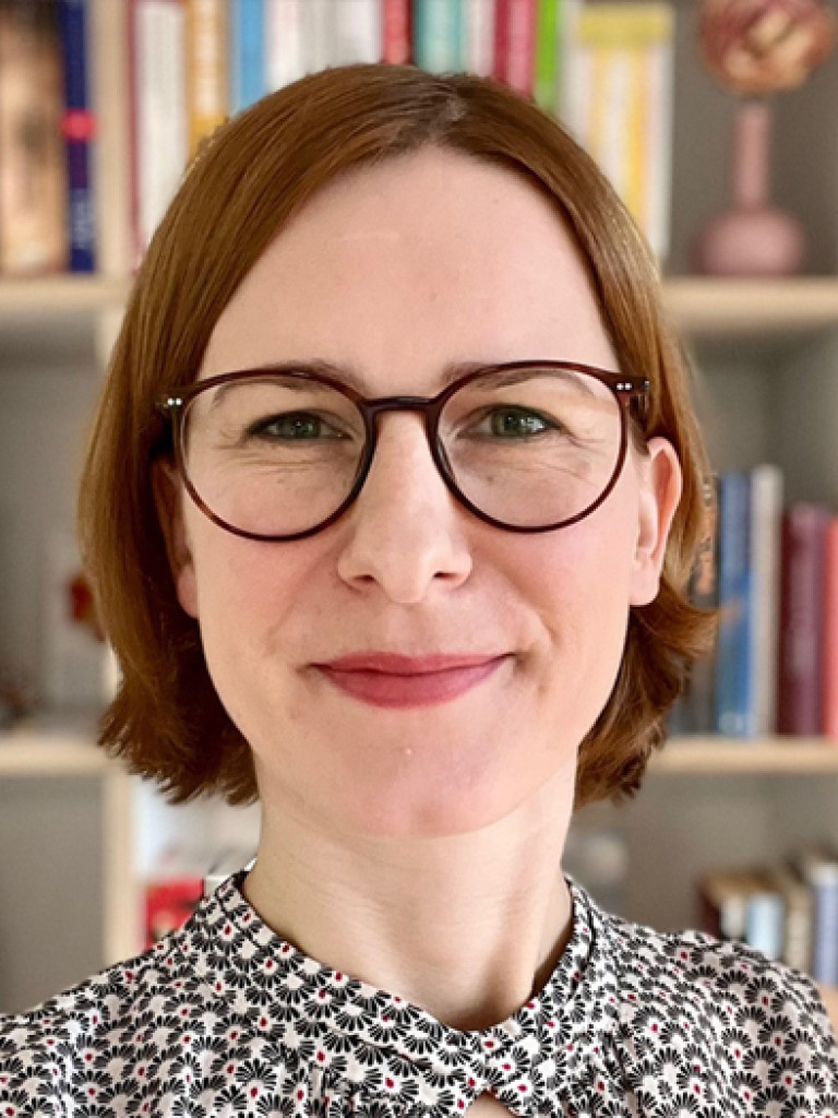 Jule Specht smiling in front of a book case
