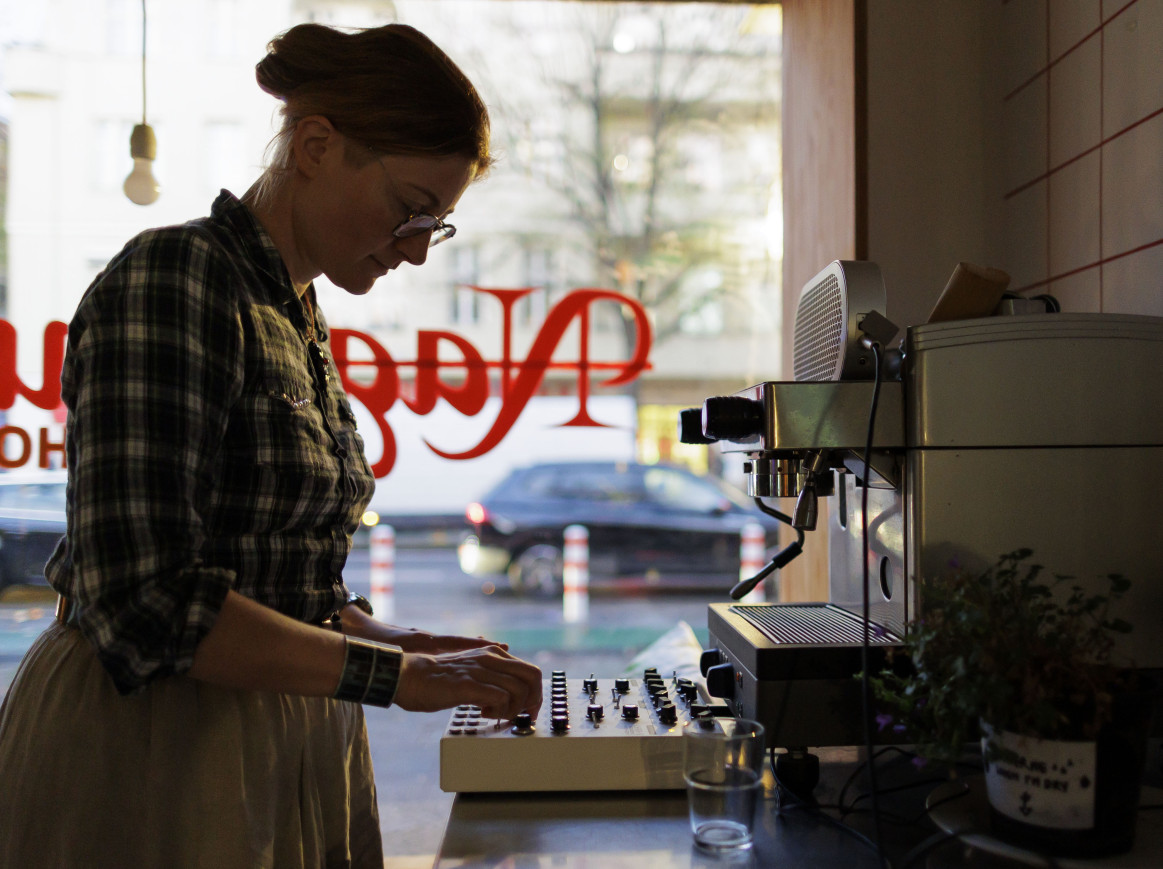 Person operating controls next to espresso machine in cozy cafe
