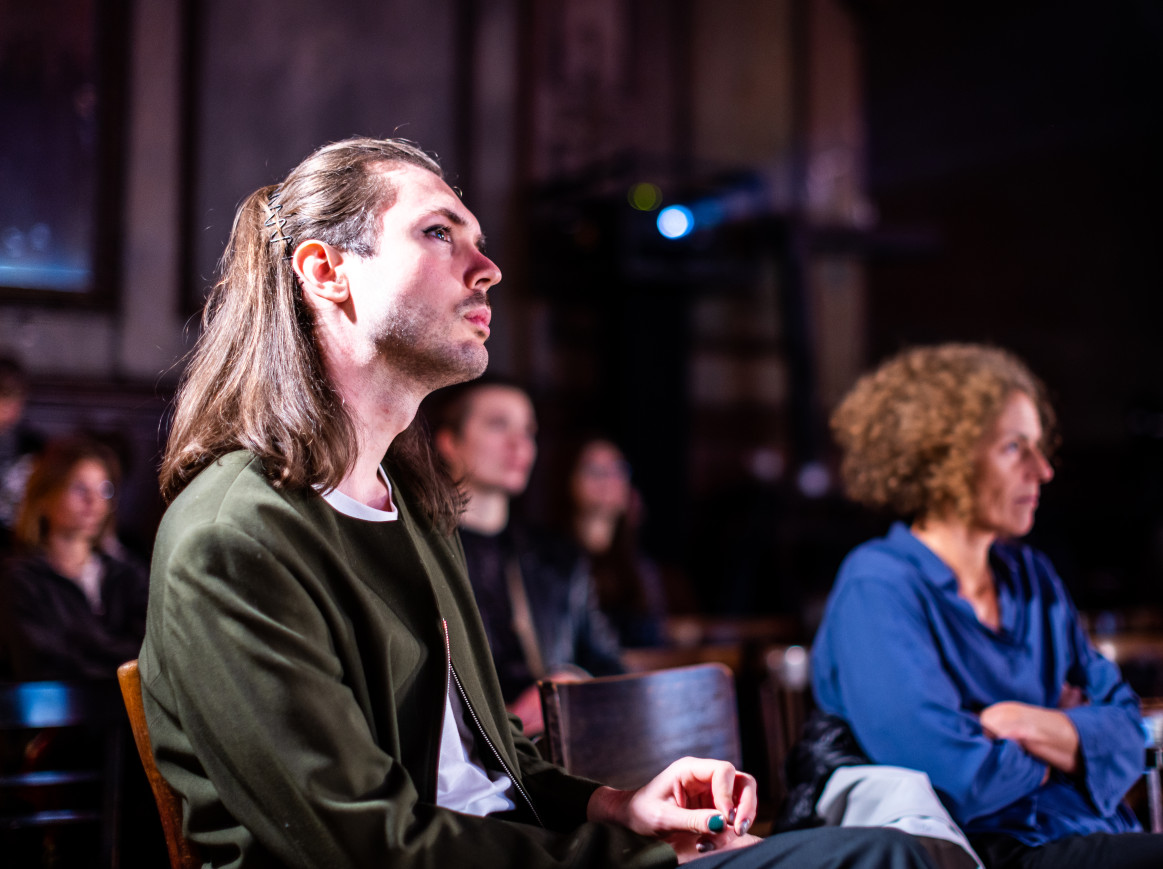 A closeup of three people looking up at a stage