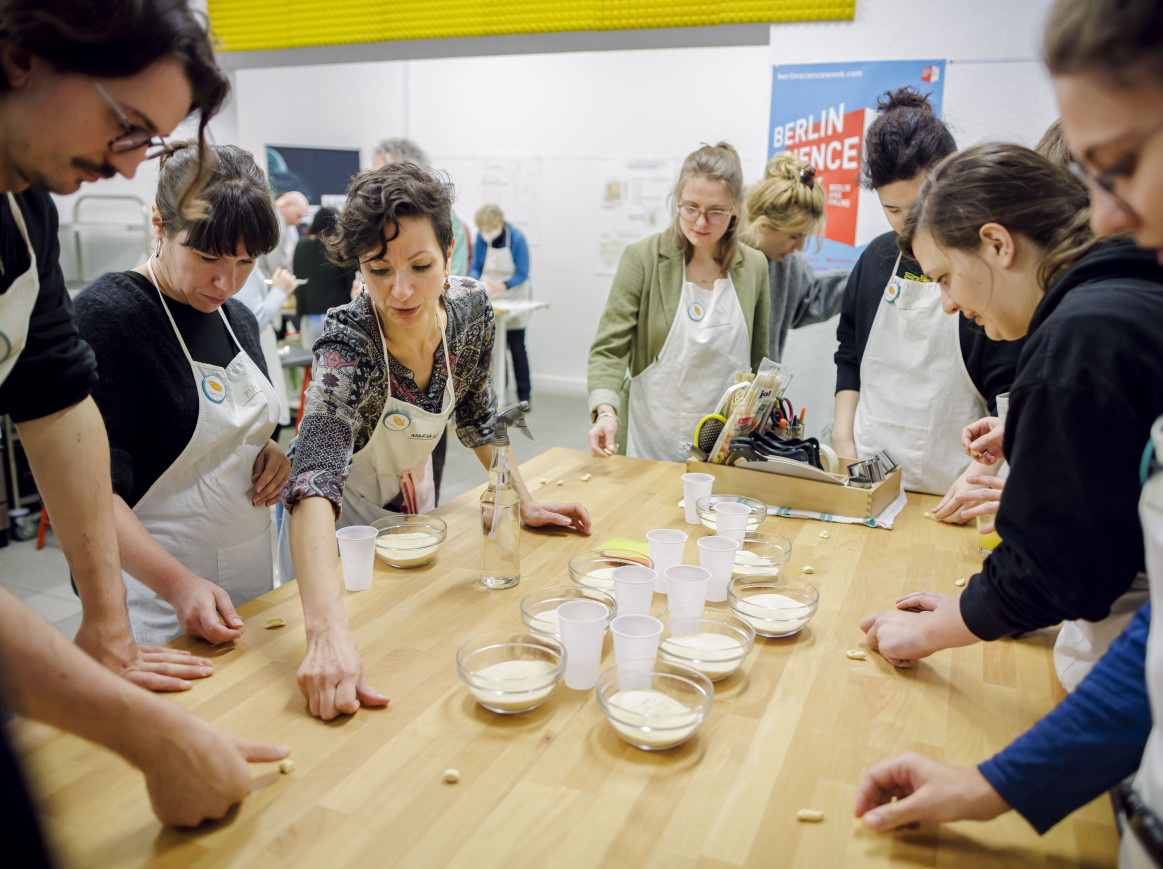 A group of people around a table making pasta