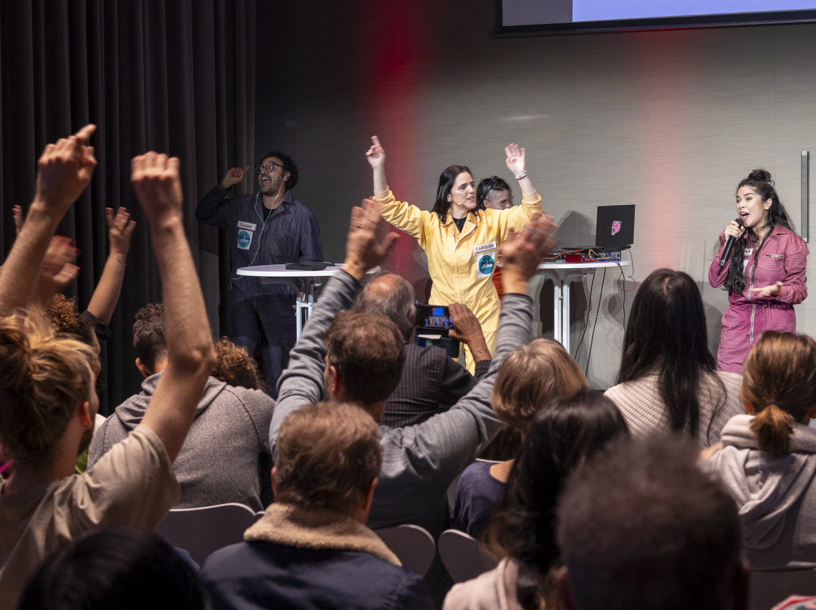 A woman on stage animating a crowd; everybody has their hands up