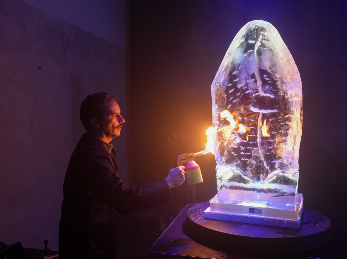 A man with a blowtorch working on an ice sculpture