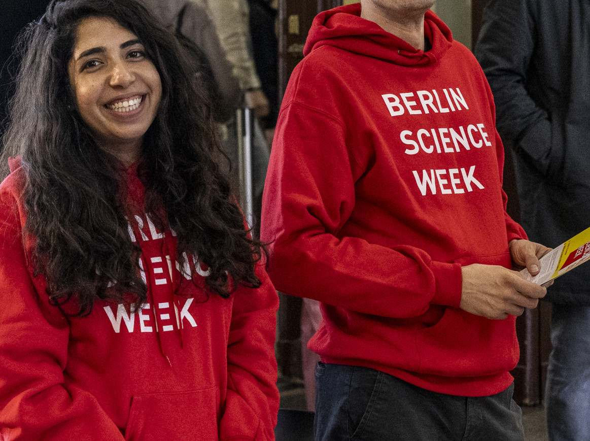 A man and a woman smiling, wearing round hoodies with the text "Berlin Science Week"