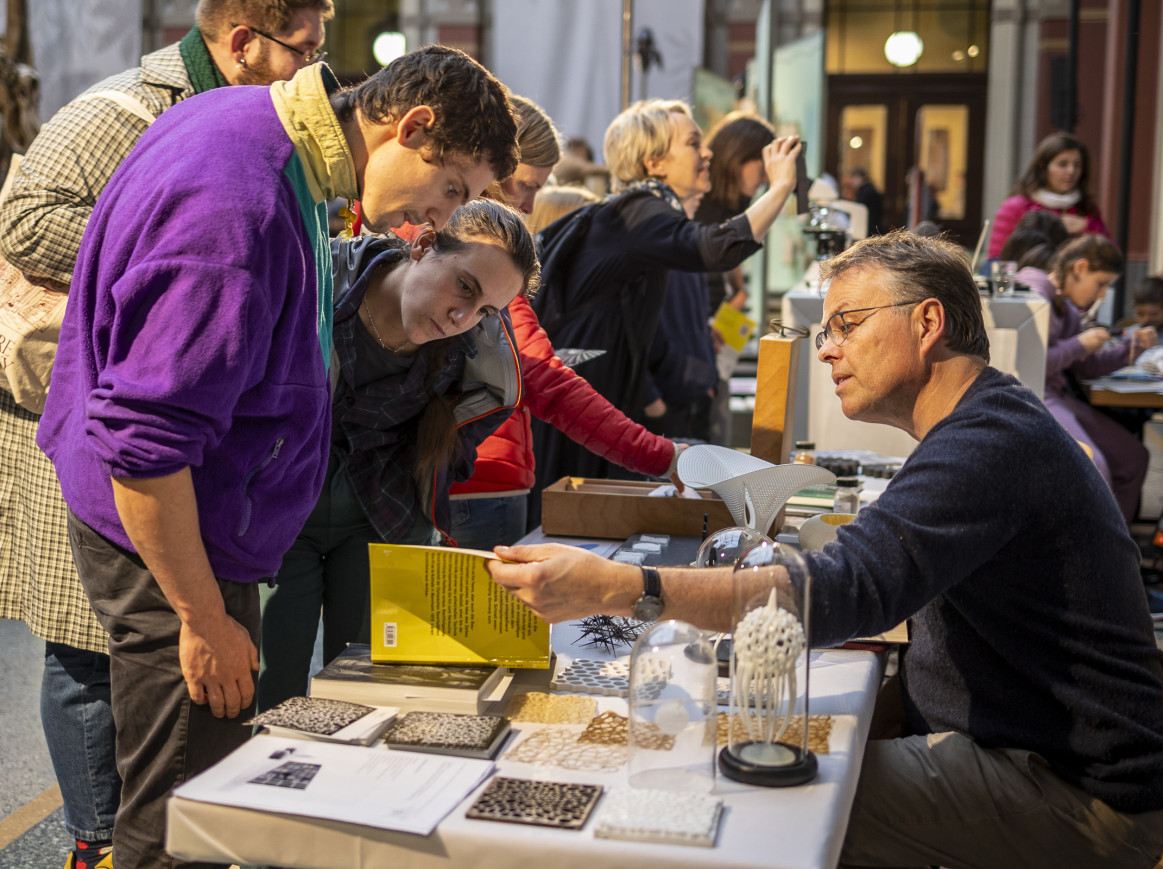 A group of people leaning over a table to look at scientific exhibits