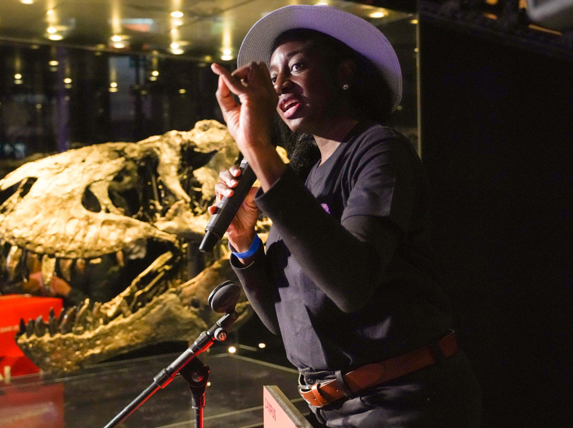 Scientist speaking about her work in front of a dinosaur skull