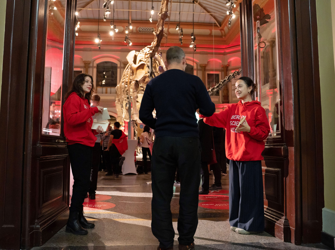 man being greeted by two volunteers when entering the dinosaur hall for the Opening of the Berlin Science Week