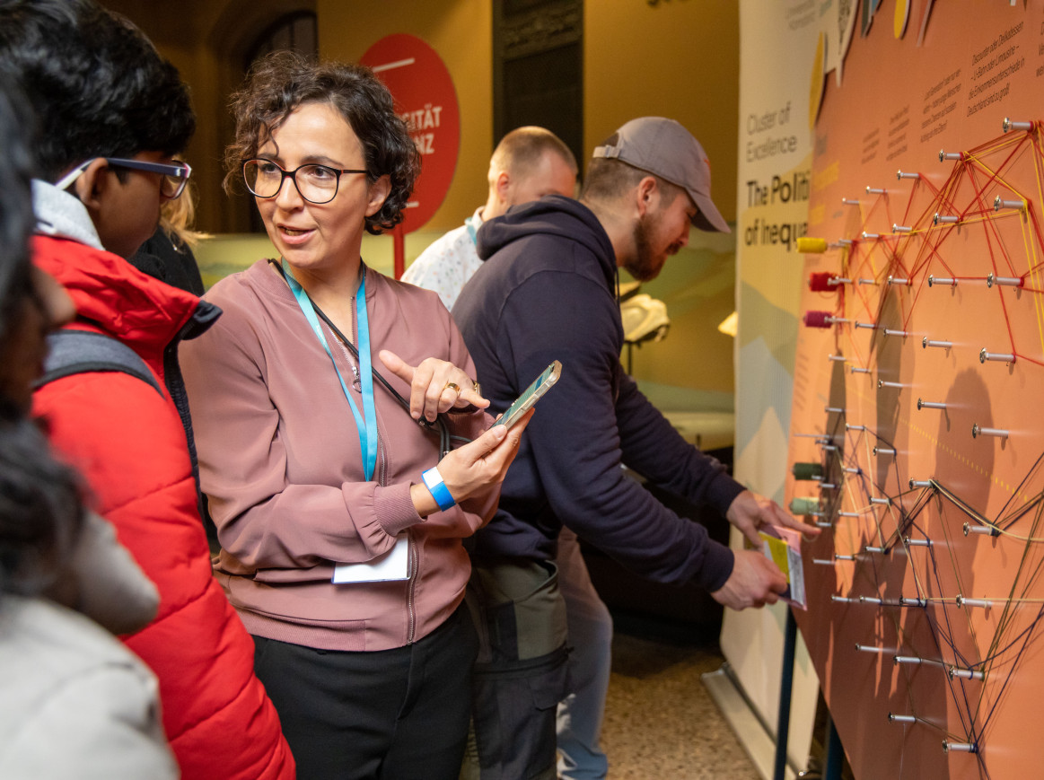 two adults standing in front of an exhibition board discussing income inequalities 