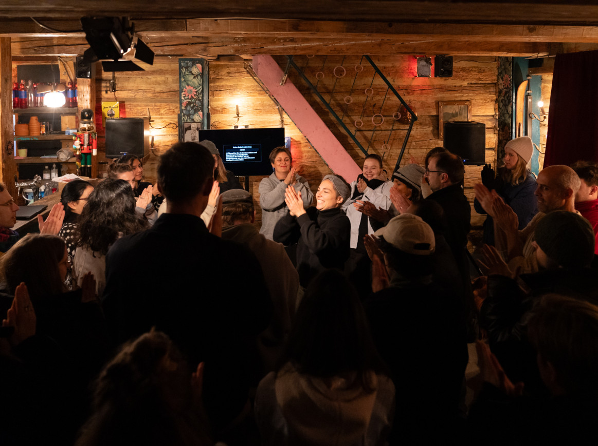 Workshop with adults gathered in a circle at the Spreelunke, rubbing their hands together