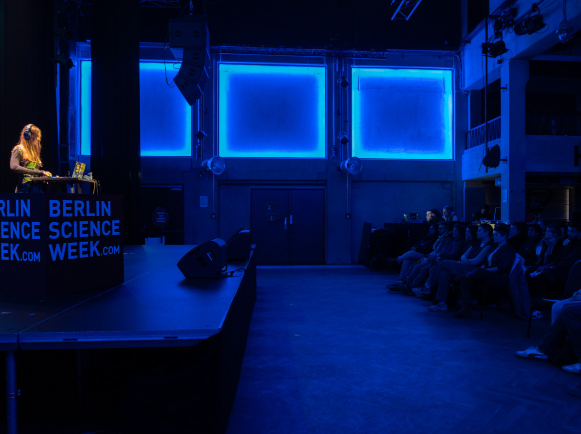 "Sara Niksic presenting her sound work on whale songs on the Säälchen stage, illuminated in blue