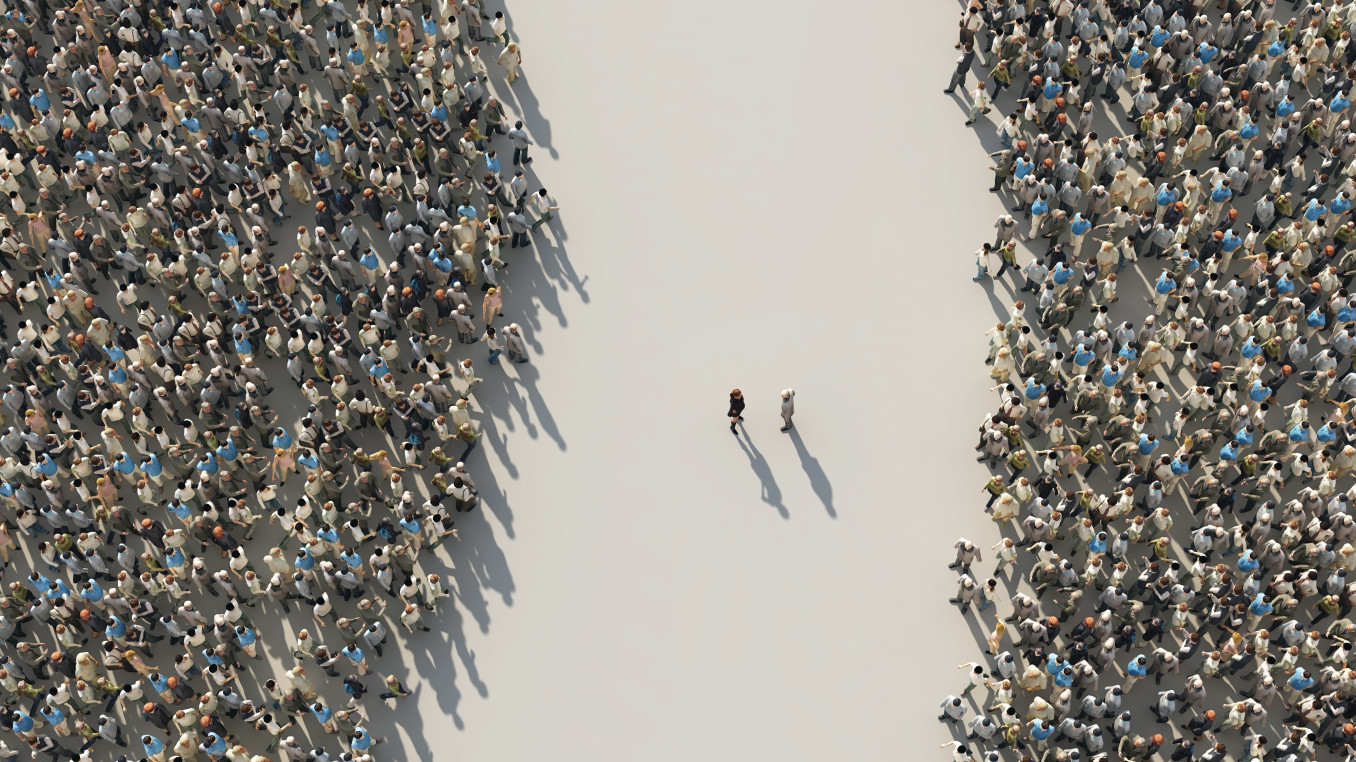 An image from above of two groups of people separated by n empty street, with two people in the middle