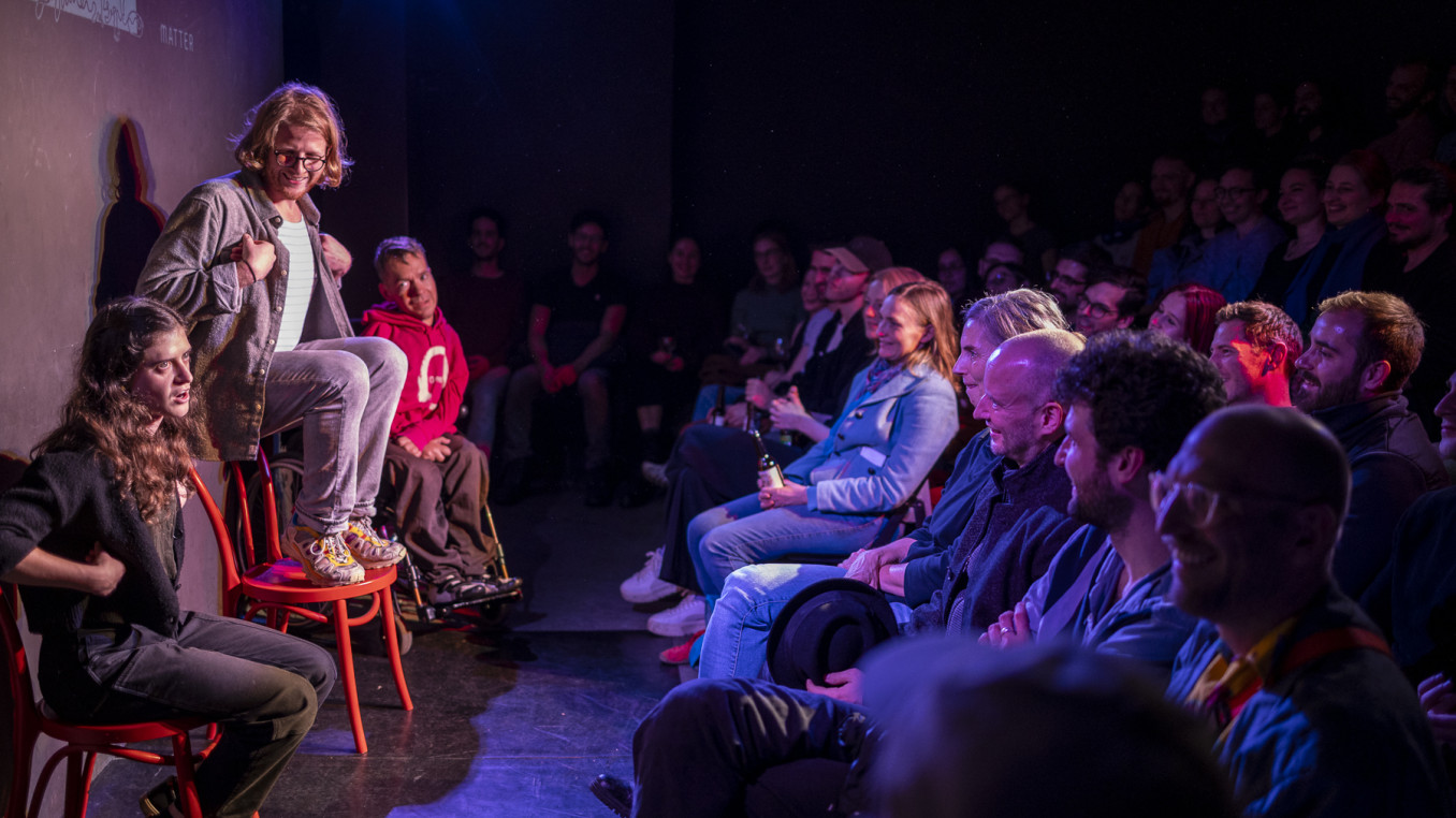 People in a room watching performers