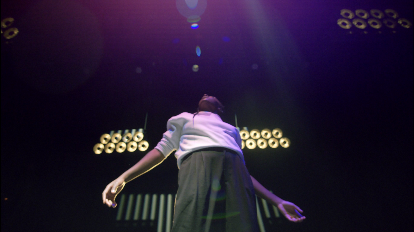  A black person standing on stage looking up