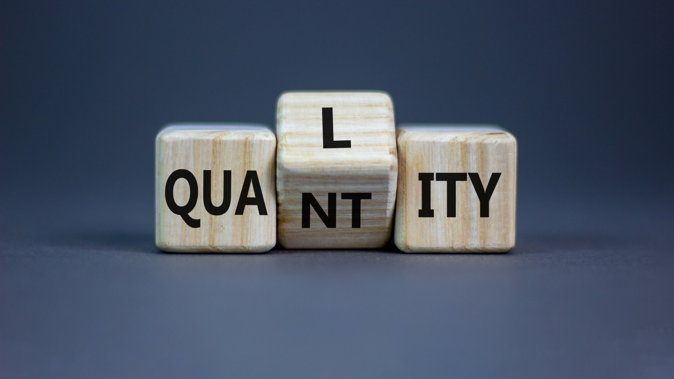A picture with wooden letters which are simultaneously spelling "Quality" and "Quantity".