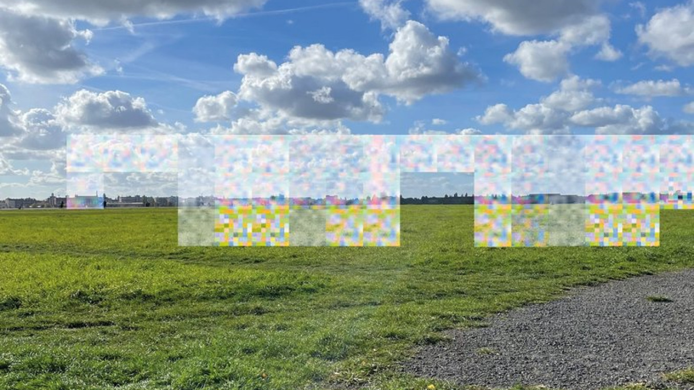 Eine weitläufige grüne Wiese unter einem blauen Himmel mit weißen Wolken. In der Mitte sind bunte, verpixelte Kästchen, die den Hintergrund verzerren.